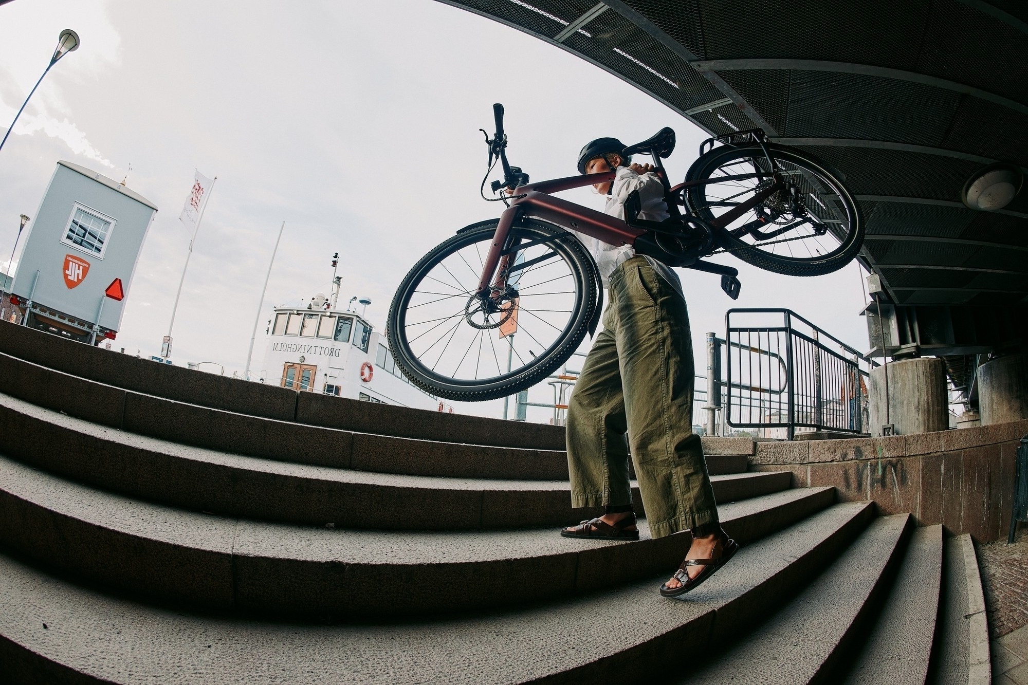 Das Bild zeigt eine Person, die ein Specialized Vado SL2 E-Bike über eine Treppe trägt.