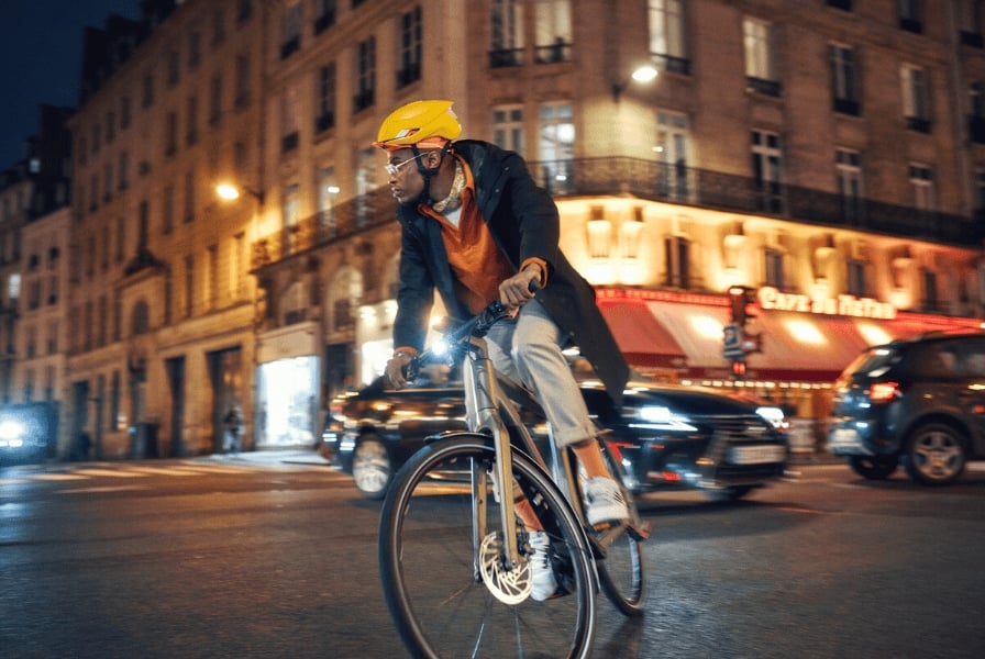 Mann mit gelbem Helm fährt Fahrrad in der Stadt bei Nacht