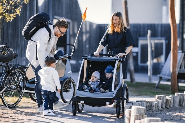 Das Bild zeigt eine Familie, die mit einem Thule Courir Kindersitz unterwegs ist.