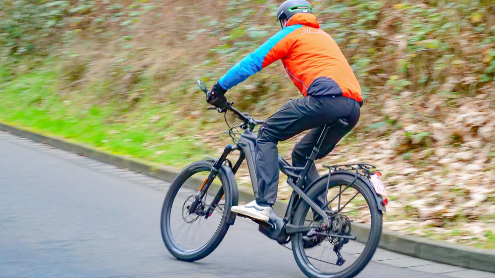 Ein Mensch fährt ein modernes E-Bike auf einer asphaltierten Straße. Perfekt für dynamische Fahrten im Freien.