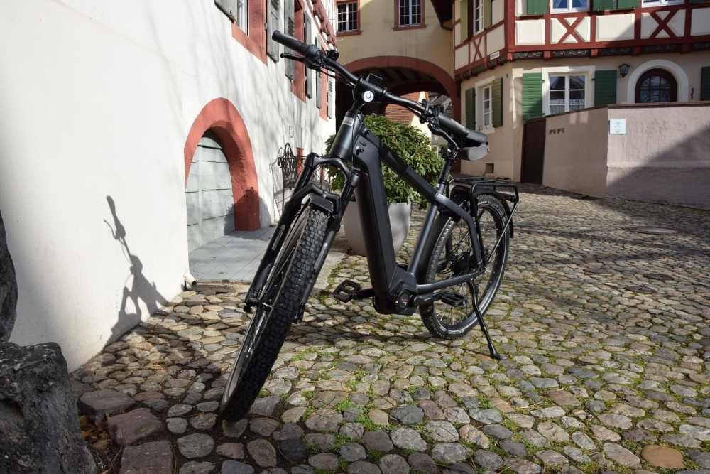 Schwarzes E-Bike Charger GT1 auf Kopfsteinpflaster vor historischem Gebäude