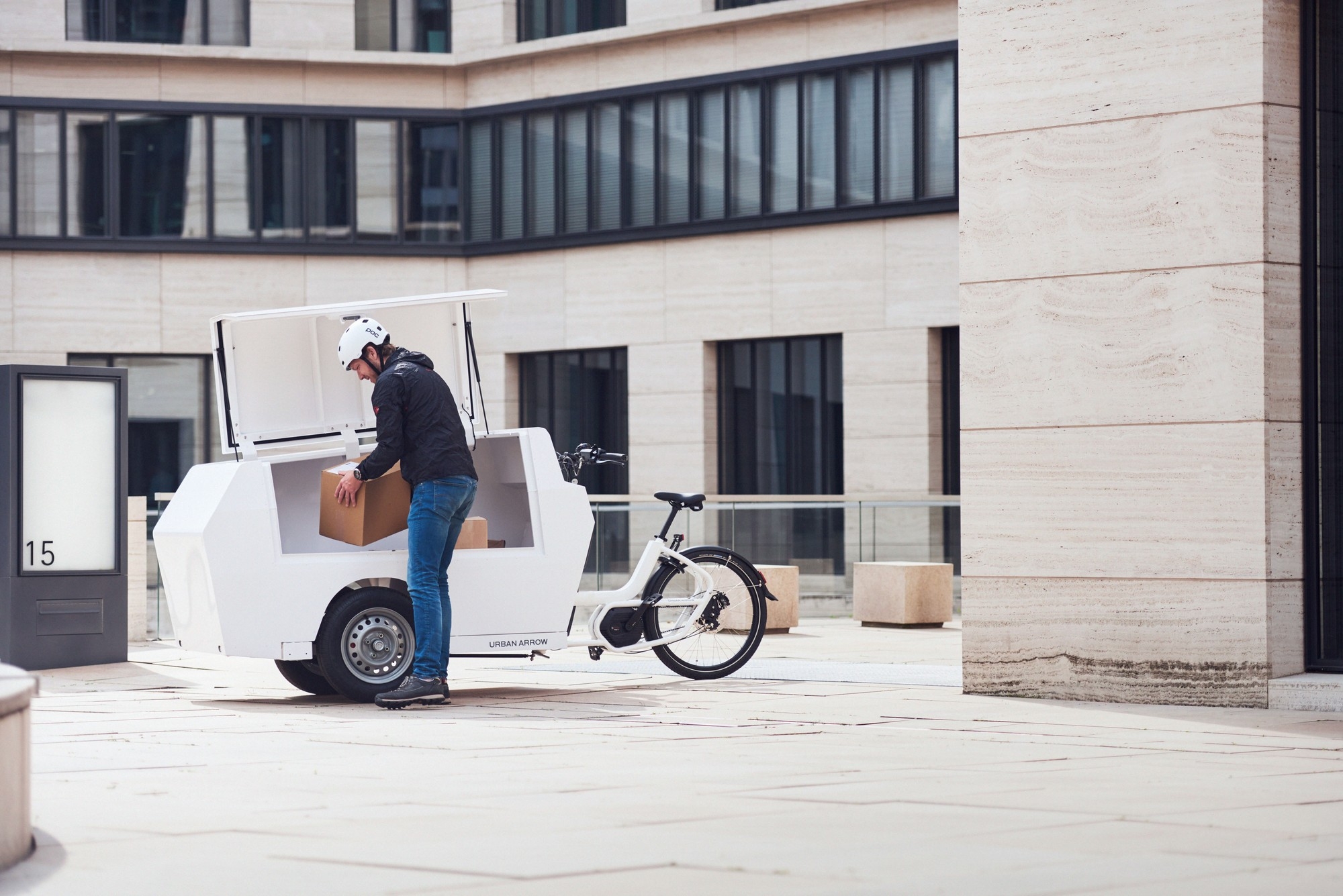 Eine Person hebt ein Paket aus dem Urban Arrow Tender Lastenrad