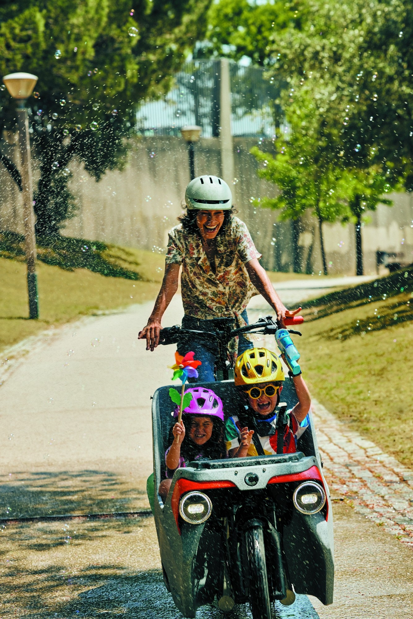 Frau fährt mit Cannondale Wonderwagen und zwei Kindern durch den Park