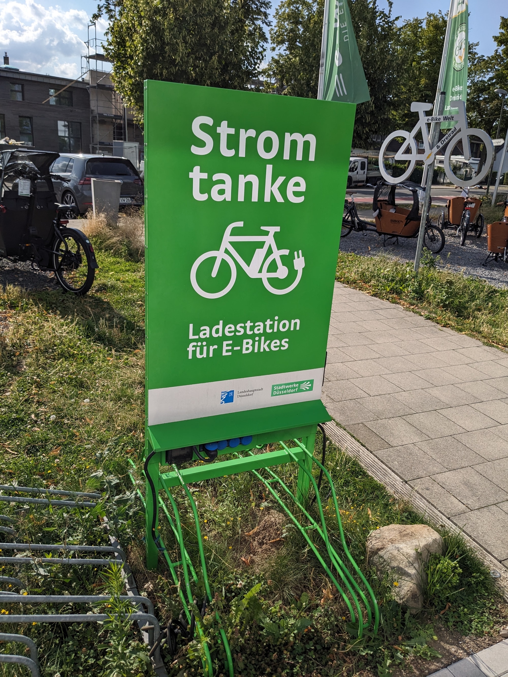 Grüne Ladestation für E-Bikes im Freien, ideal für umweltfreundliches Aufladen unterwegs.