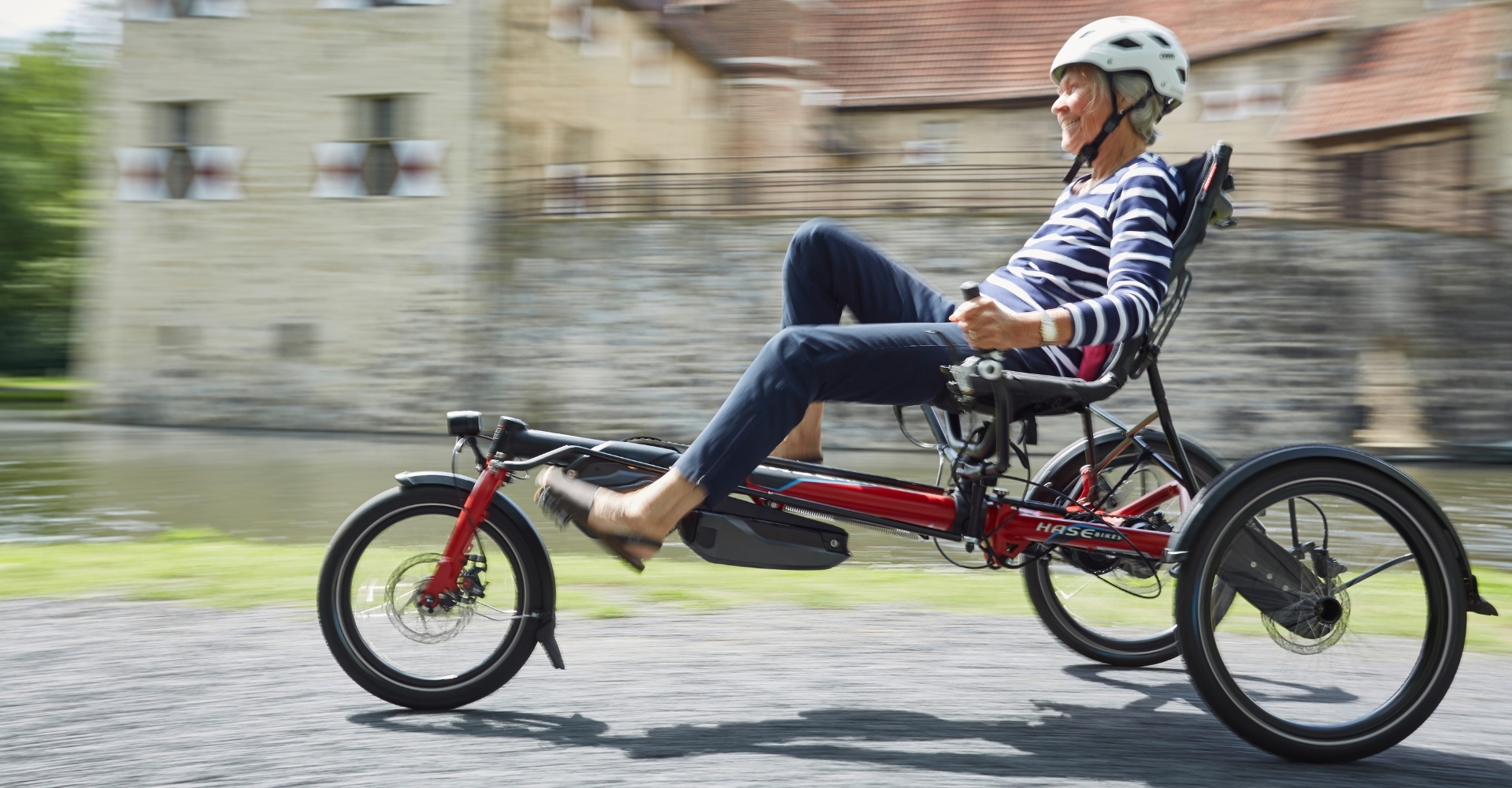 Das Bild zeigt eine ältere Frau, die ein HASE BIKES Lepus fährt.