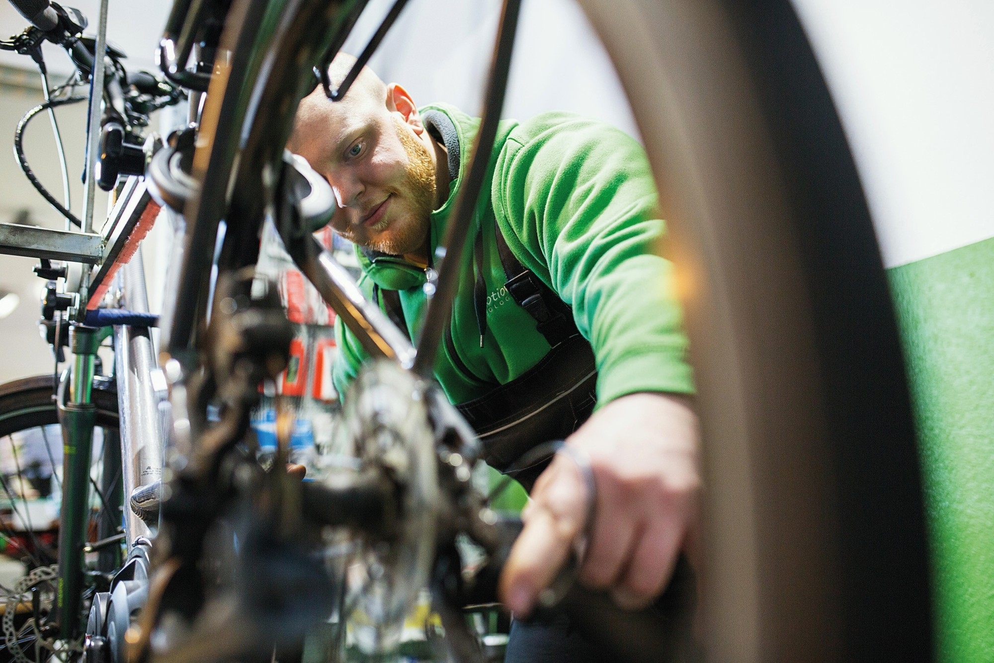 Auf dem Bild ist ein Mechaniker zu sehen, der in einer Werkstatt von e-motion an einem E-Bike arbeitet.