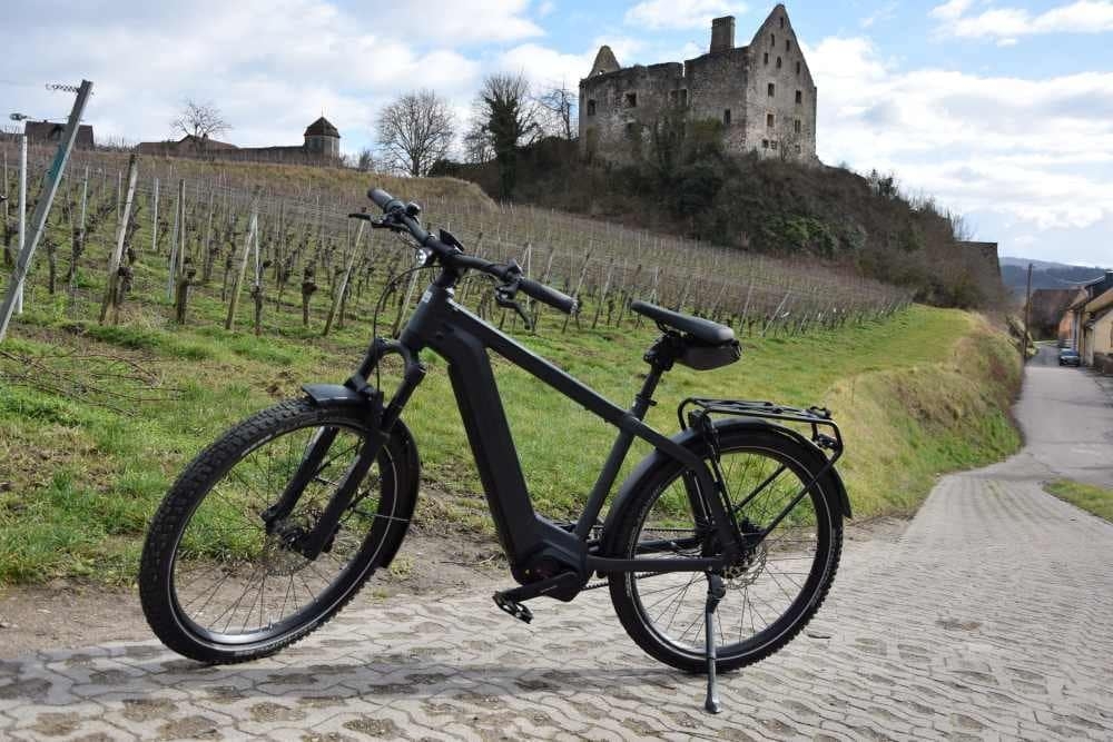 Schwarzes E-Bike vor einer Ruine in ländlicher Landschaft