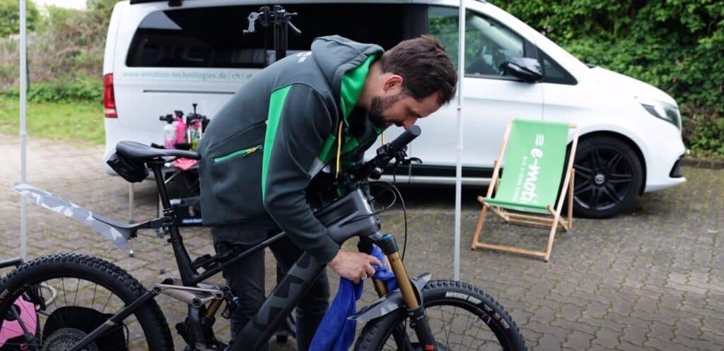 Mann pflegt Mountainbike vor einem Transporter im Freien