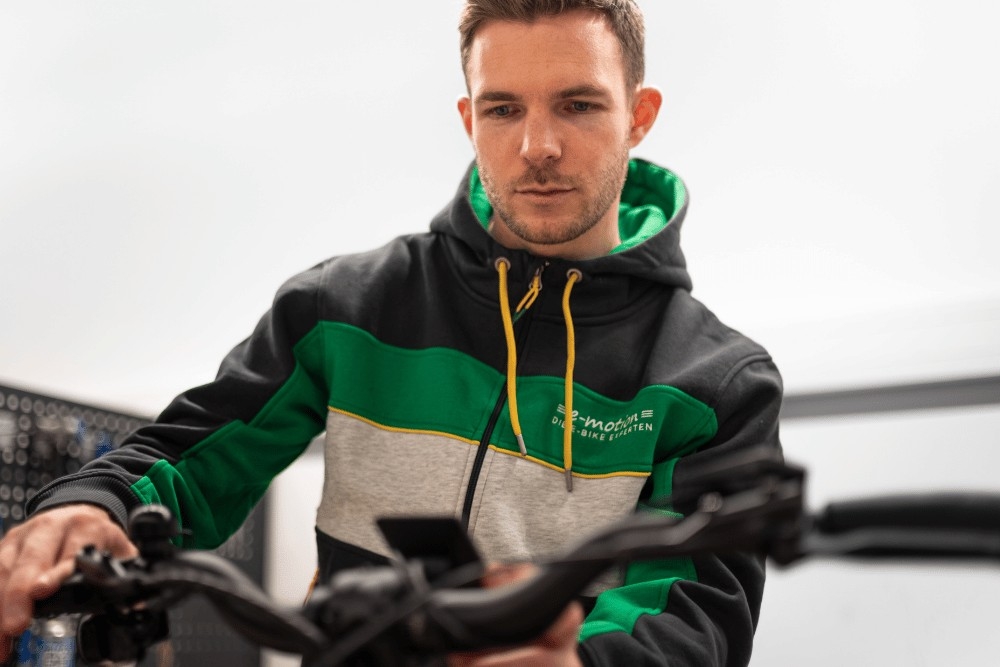 Das Bild zeigt einen Mechaniker, der sorgfältig die Bremsen eines e-Bikes überprüft.