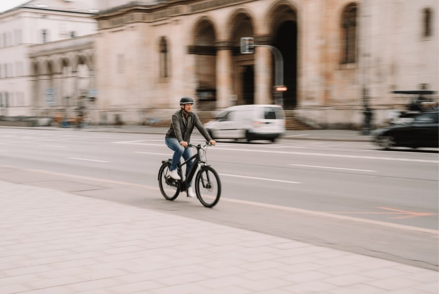 Person fährt E-Bike auf städtischer Straße mit historischen Gebäuden
