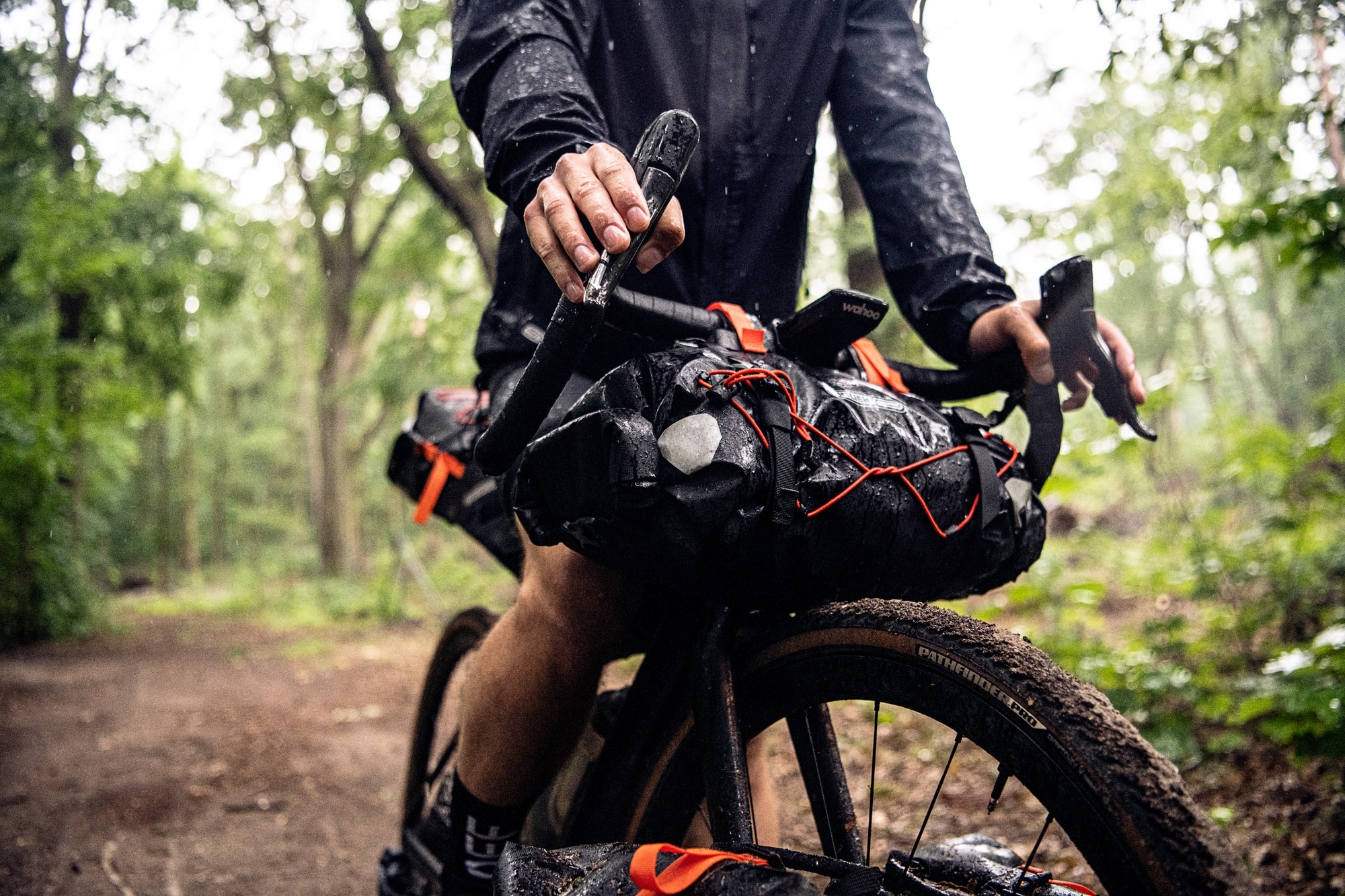 Ein Radfahrer mit Lenkertasche und Wahoo-Gerät auf Waldweg. Perfekt für Bikepacking-Abenteuer.