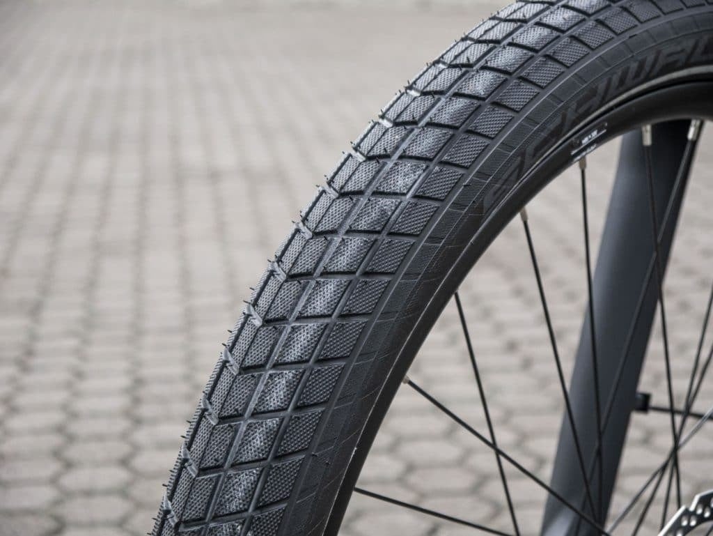 Nahaufnahme eines Fahrradreifens mit Profil auf gepflastertem Untergrund