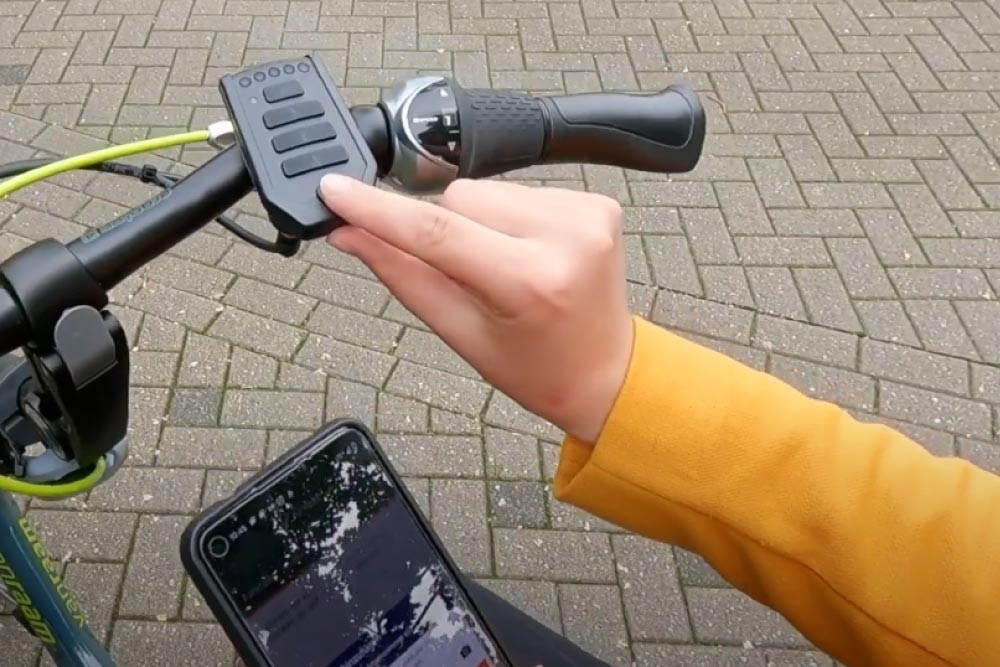 Ein Handy im Hintergrund sowie das Van Raam Dreirad im Vordergrund, dass sich mit der App verknüpft